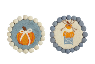 Round felted wool pumpkin topiary trivets with pom-pom trim featuring embroidered pumpkin and pumpkin topiary designs in soft blue, cream, and orange.
