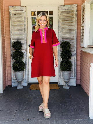 Rory Burgundy Dress with pink and orange contrast trim, mock neck, front zip detail, short sleeves, and side pockets.Rory Burgundy Dress with pink and orange contrast trim, mock neck, front zip detail, short sleeves, and side pockets.