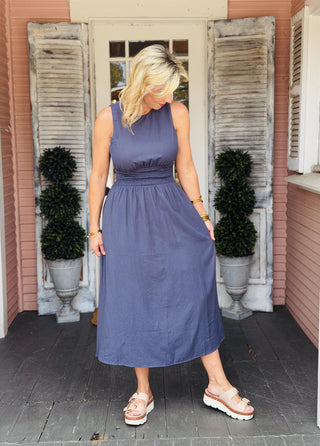 Elle Dress in navy featuring a boat neckline, smocked waist, midi length, and open cutout back.