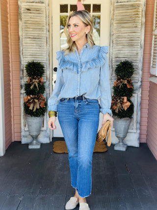 Woman wearing light denim ruffle button-up top

Chambray ruffle yoke denim blouse with collar

Josie Denim Top with shirred ruffle detail

Light blue high-low hem denim shirt for women

Feminine chambray button-up with long sleeves
