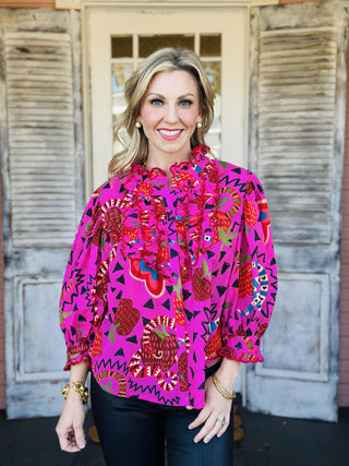 Bright pink Sabrina Charming Top with ruffles and bold print

Colorful patterned blouse with snakes, hearts, and ruffled neckline

Pink ruffle-front top with vibrant artistic print

Statement blouse with whimsical multicolor pattern and buttons