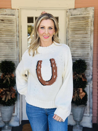 Woman wearing ivory knit horseshoe sweater with cowboy hat

Western-style ivory sweater with brown horseshoe design

Dolly Sweater with bold horseshoe motif and relaxed fit

Ivory Western knit sweater with ribbed hem and sleeves

Cozy horseshoe intarsia sweater with long sleeves