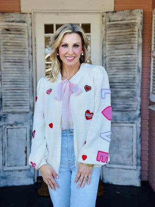 Valentine Patch Cardigan cream knit with red heart patches

Cream cardigan sweater with embroidered hearts and LOVE sleeve

Romantic heart patch cardigan with front tie detail

Cozy cream knit cardigan with red and pink heart accents

Valentine heart cardigan sweater with long sleeves