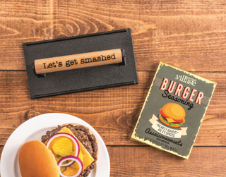 Grill Press & Seasoning Set with cast iron grill press, wooden "Let's Get Smashed" handle, and Gourmet Village Burger Seasoning packet.
