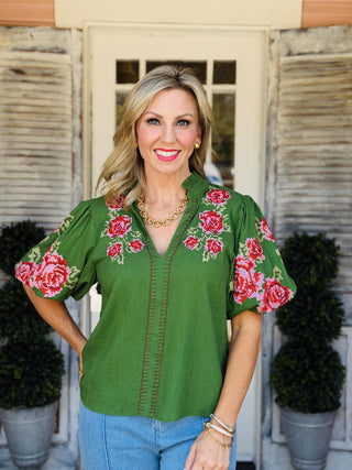 Green Kenleigh Top with red and pink floral embroidery, V-neckline, and puff sleeves.