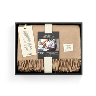 Soft camel Giving Wrap with fringe trim displayed on mannequin.

Camel Giving Wrap in gift box with sentiment tag and “Handmade with Love” label.

Cozy camel wrap with fringe from the Giving Collection by Demdaco.